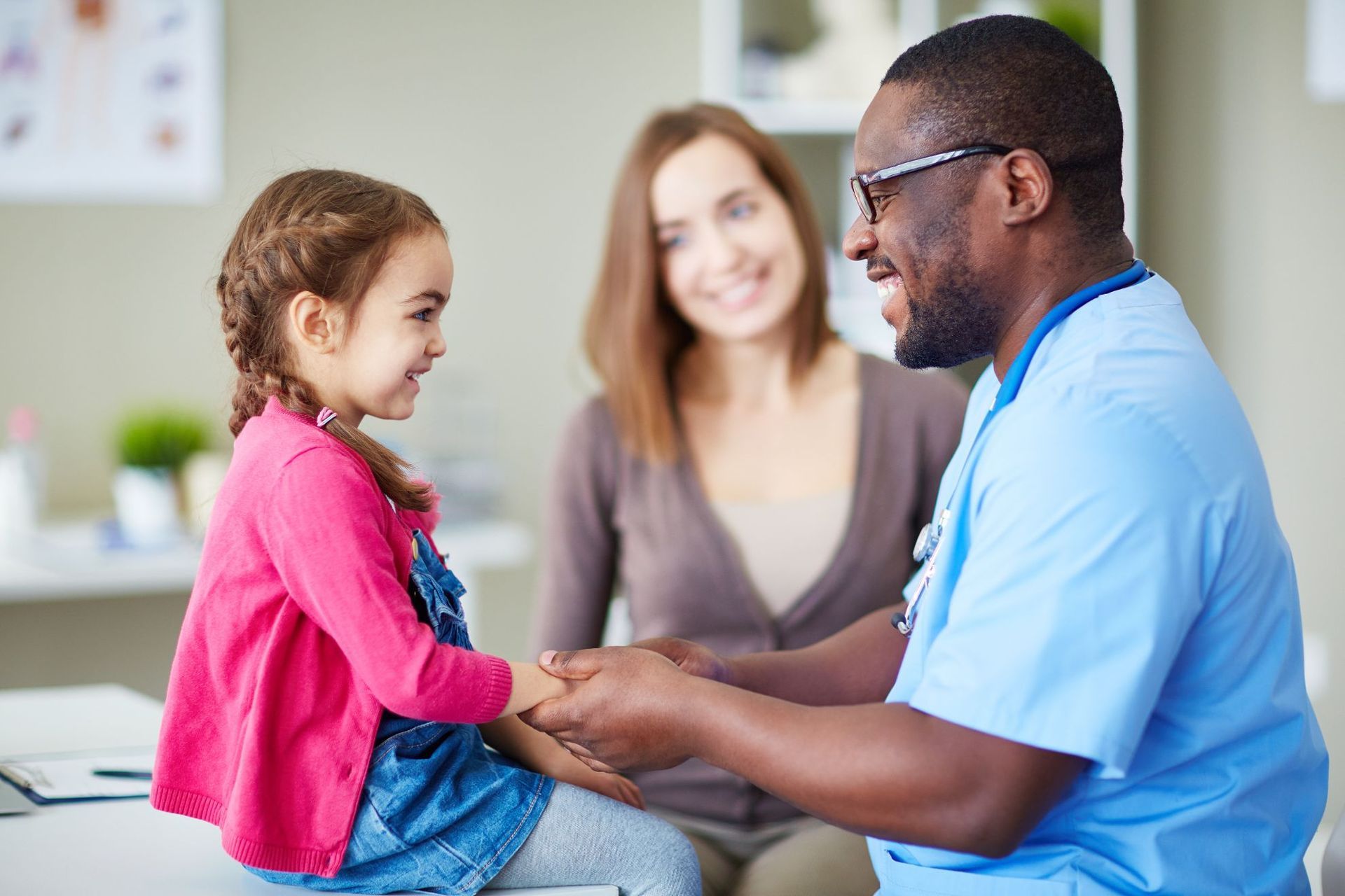 A doctor is holding the hand of a little girl.