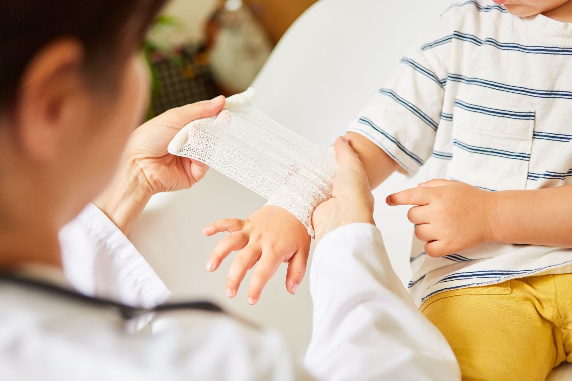A doctor is applying a bandage to a child 's hand.